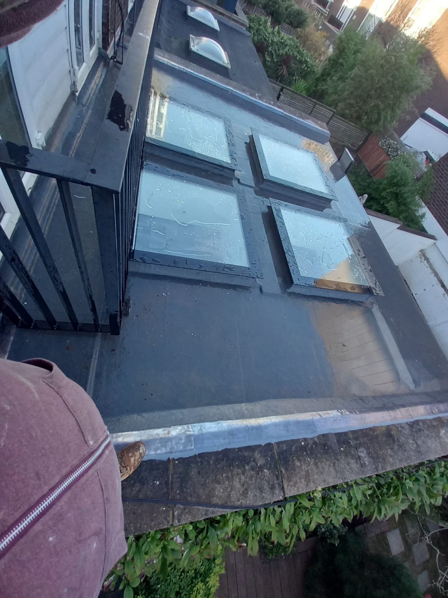 Fibreglass flat roof with multiple skylights and balcony railing — aerial view in North London