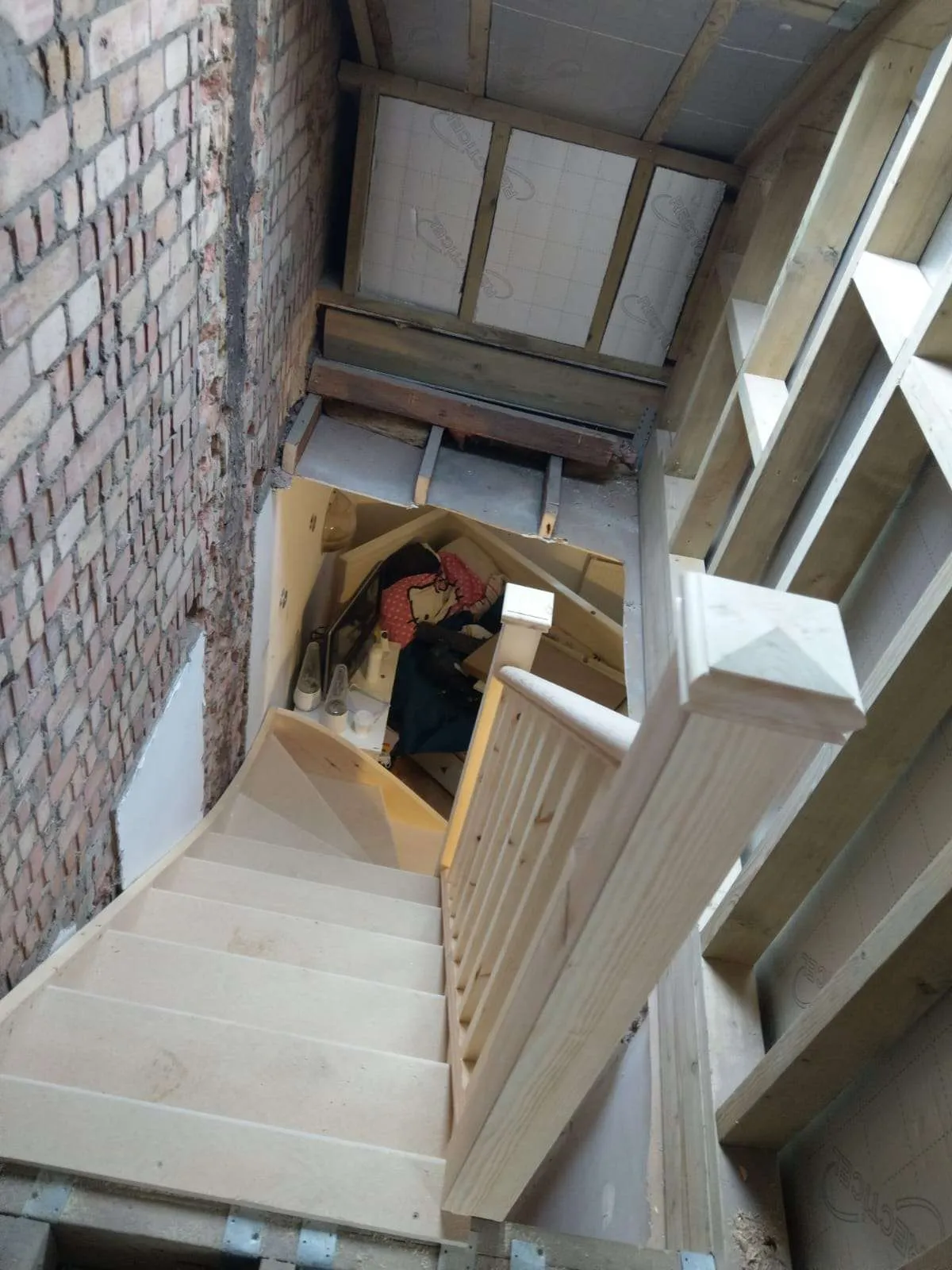 Loft conversion staircase under construction with pine balustrade and exposed brickwork