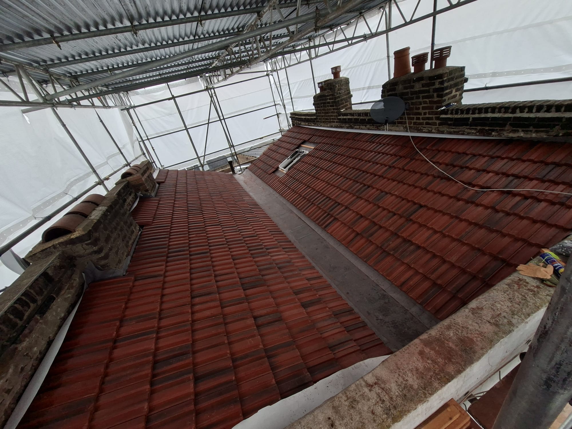 New clay tile roof installation with scaffolding on London property