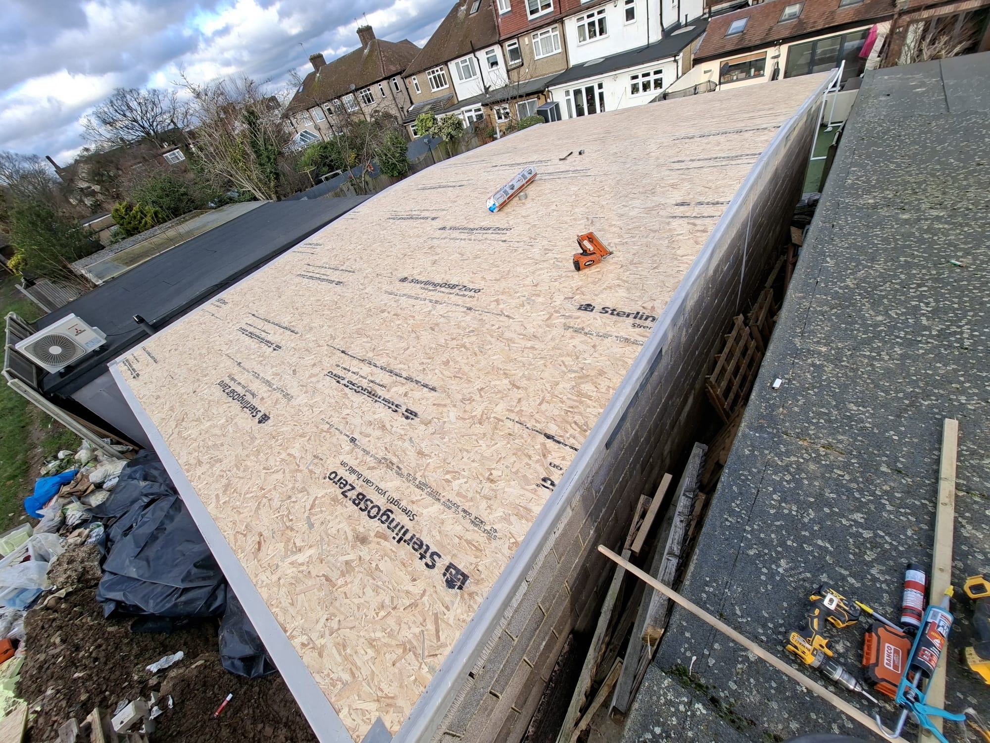 OSB board flat roof with roofing tools during felt installation