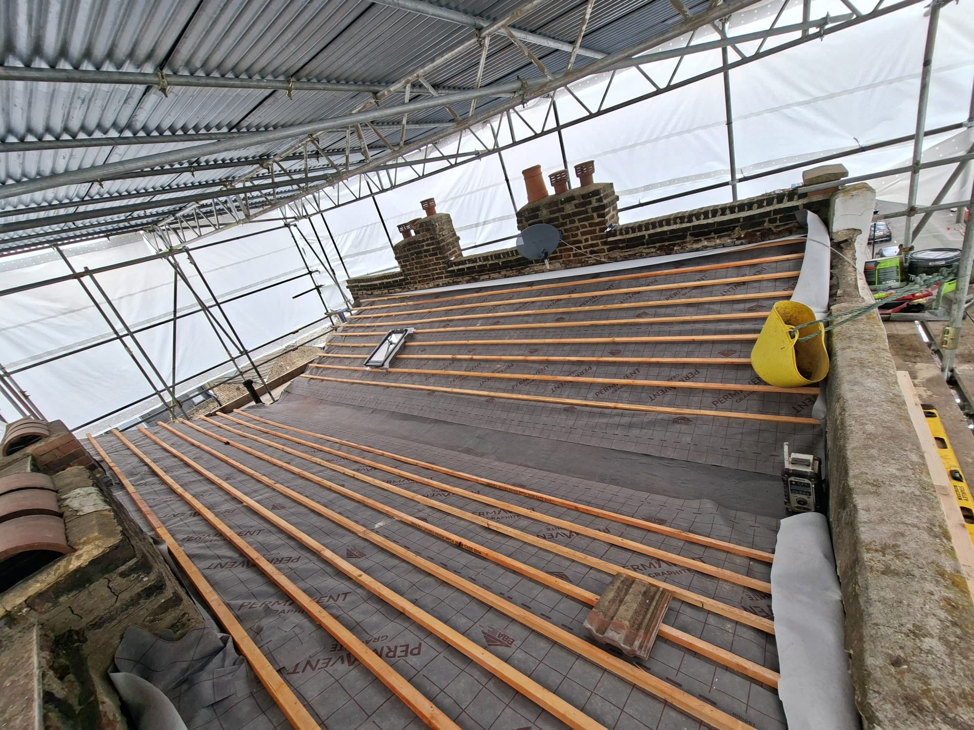 Roof replacement in progress with new battens and scaffolding