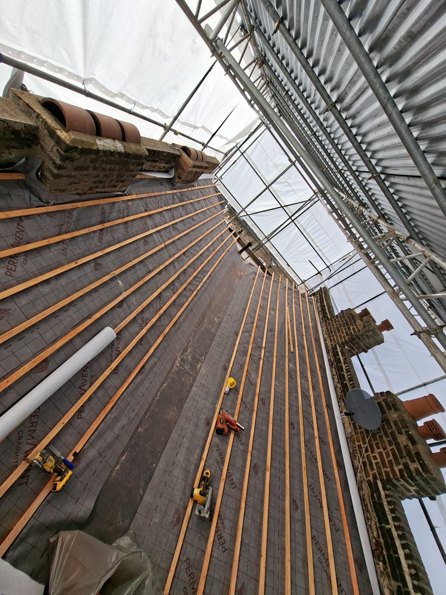 Roof replacement battens laid over membrane with scaffolding