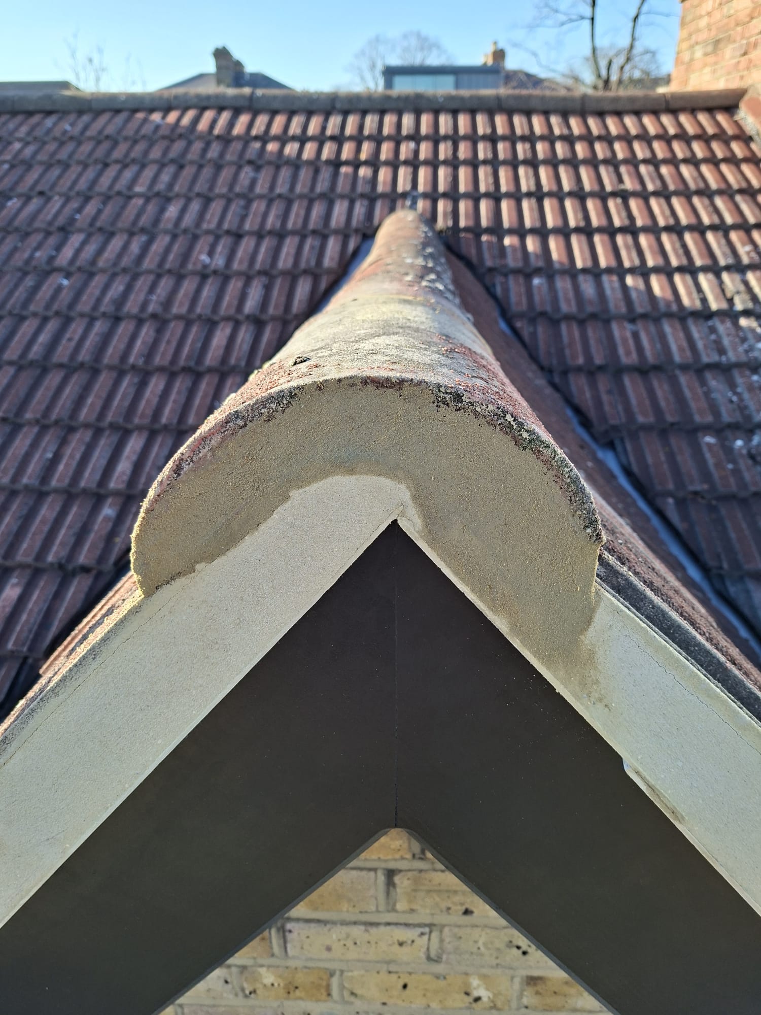 Roof ridge tiles with fresh mortar bedding on pitched roof
