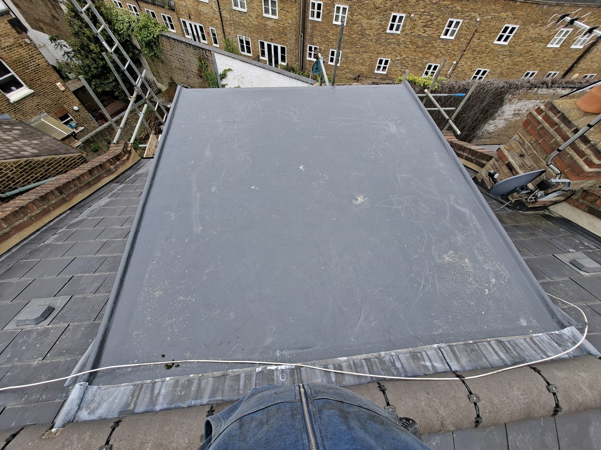 Rubber flat roof aerial view between slate rooftops in London